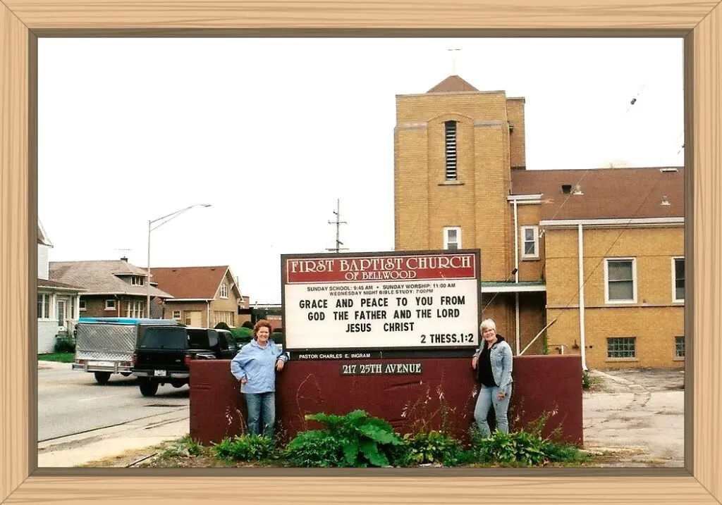 me and my sister as adults standing in front of the Bellwood Baptist Church sign