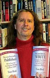 Tom is holding two of his published books in front of his library and link to his website,