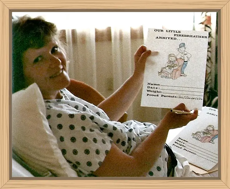 I am holding an announcement that says Our Little Firebreather Arrived, without the name, date, or weight filled in. The picture is a cartoon of Pete in his Dairy uniform and me sitting and holding a baby dragon.