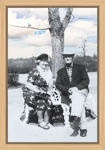 My grandparents on my mother's side sitting together outside under a tree