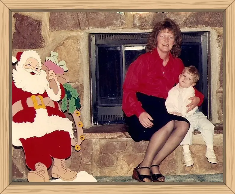 Hayes and I dressed up and sitting by the fireplace with a large Santa decoration nearby.