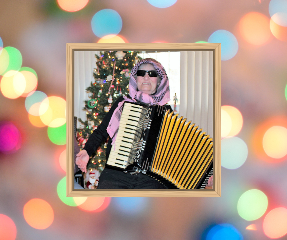 Me with a babushka and shades on playing my $1.00 accordion in front of the Christmas tree.