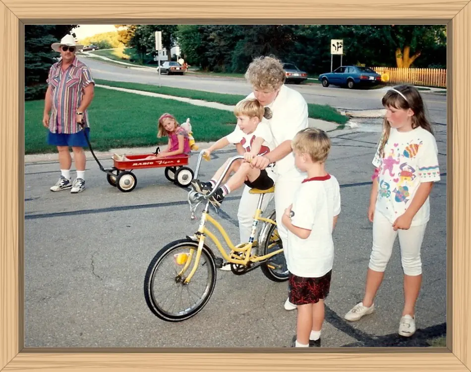 My sister is trying to steady Hayes on the handlebars of her bike while Pete and the cousins look on.
