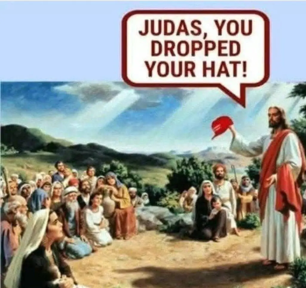 Jesus is standing and holding a red MAGA hat in front of a large group of people who came to hear him speak about being a kind and faithful person.