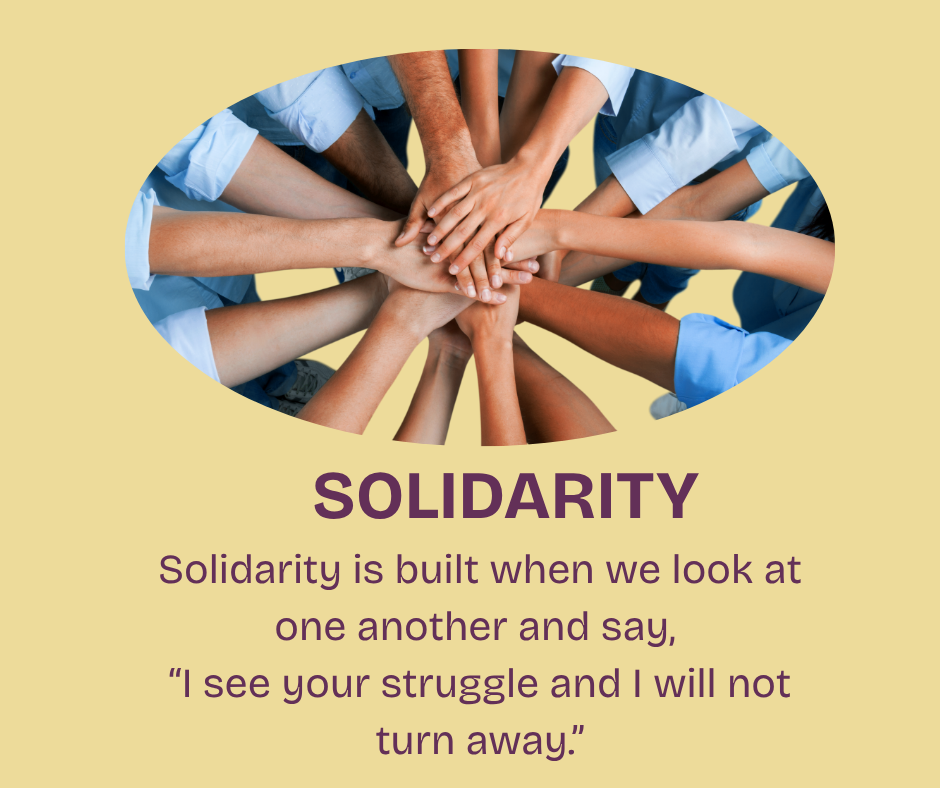 A tight circle of hands of many different shades joining in the middle, showing solidarity for one another.