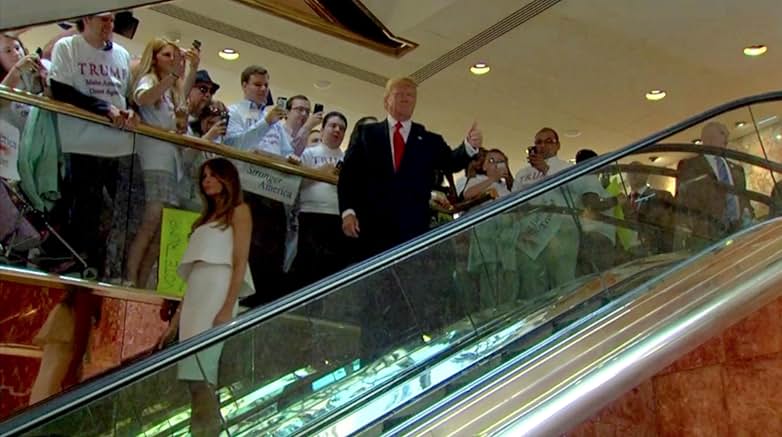 There is a crowd around the escalator watching them from above.